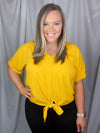 Top features a solid base color, V-neck line, cuffed short sleeves, front waist tie detail, loose fit and runs true to size! -mustard