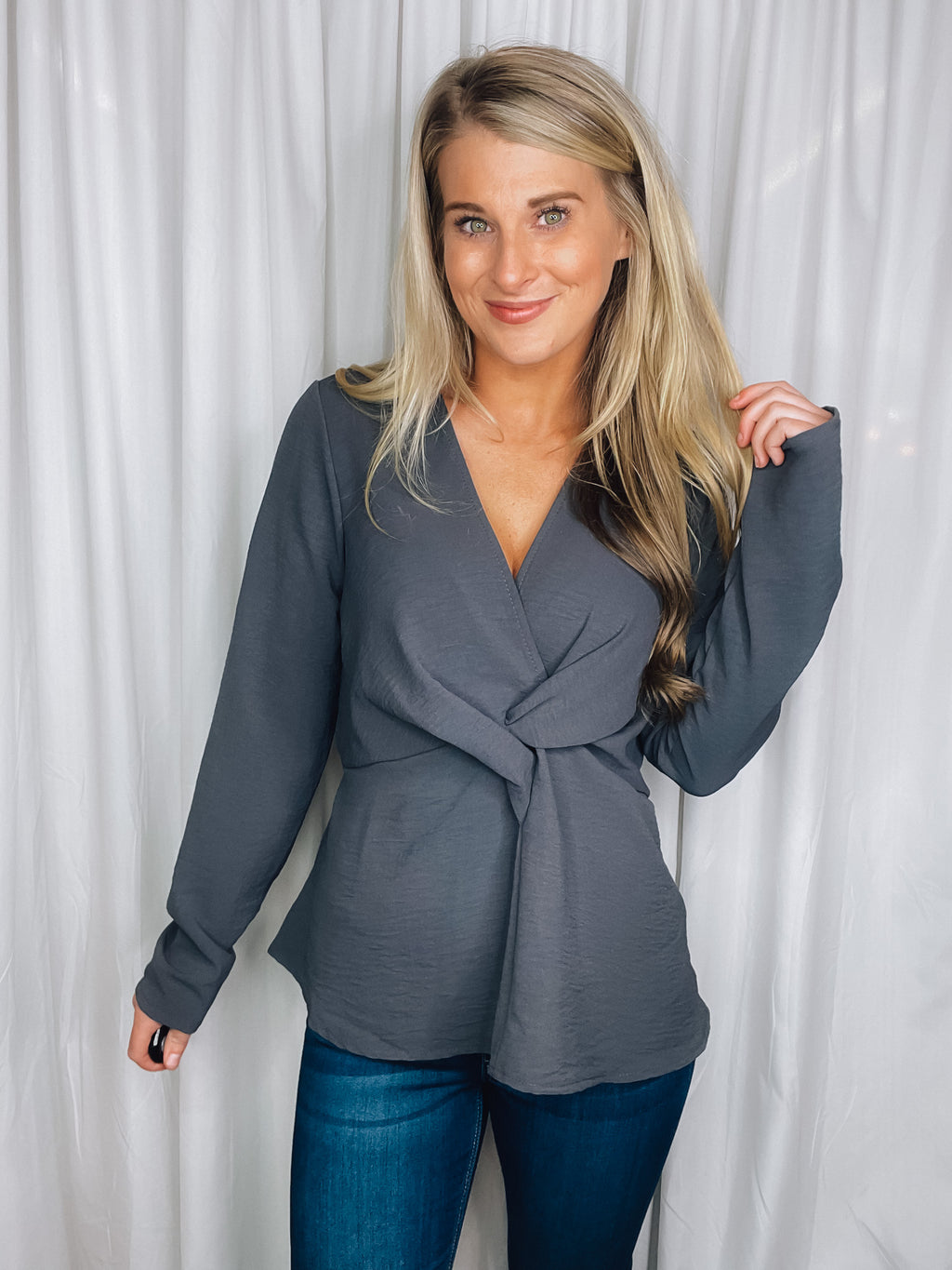 Top features a charcoal base, long sleeves, V-neck line, peplum fit, front knot detail, and runs true to size! 