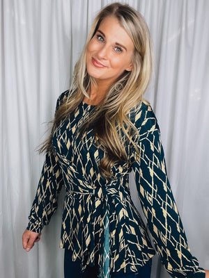 Top features a hunter green base, cream abstract print, long sleeves, V-neck line, tie front detail and runs true to size! 