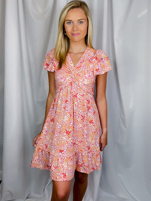 Dress features a coral/ lavender floral print, short sleeves, front knot detail, short sleeves, ruffle detailing and runs true to size! 