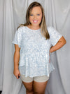 Top features an ivory base, beautiful pale blue floral print, short sleeves, flattering ruffle bottom hem, round neck line and runs true to size! 