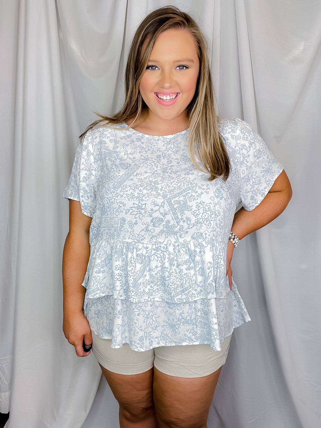 Top features an ivory base, beautiful pale blue floral print, short sleeves, flattering ruffle bottom hem, round neck line and runs true to size! 