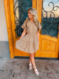 This mini dress is perfect for a sunny outing. Its tan hue, short sleeves, and side cutouts elegantly balance the abstract print, making it an ideal choice for those looking to look stylish and stay cool. Vacay ready, this piece is sure to be a crowd pleaser.