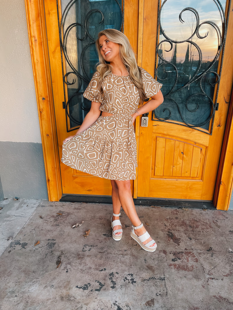 This mini dress is perfect for a sunny outing. Its tan hue, short sleeves, and side cutouts elegantly balance the abstract print, making it an ideal choice for those looking to look stylish and stay cool. Vacay ready, this piece is sure to be a crowd pleaser.