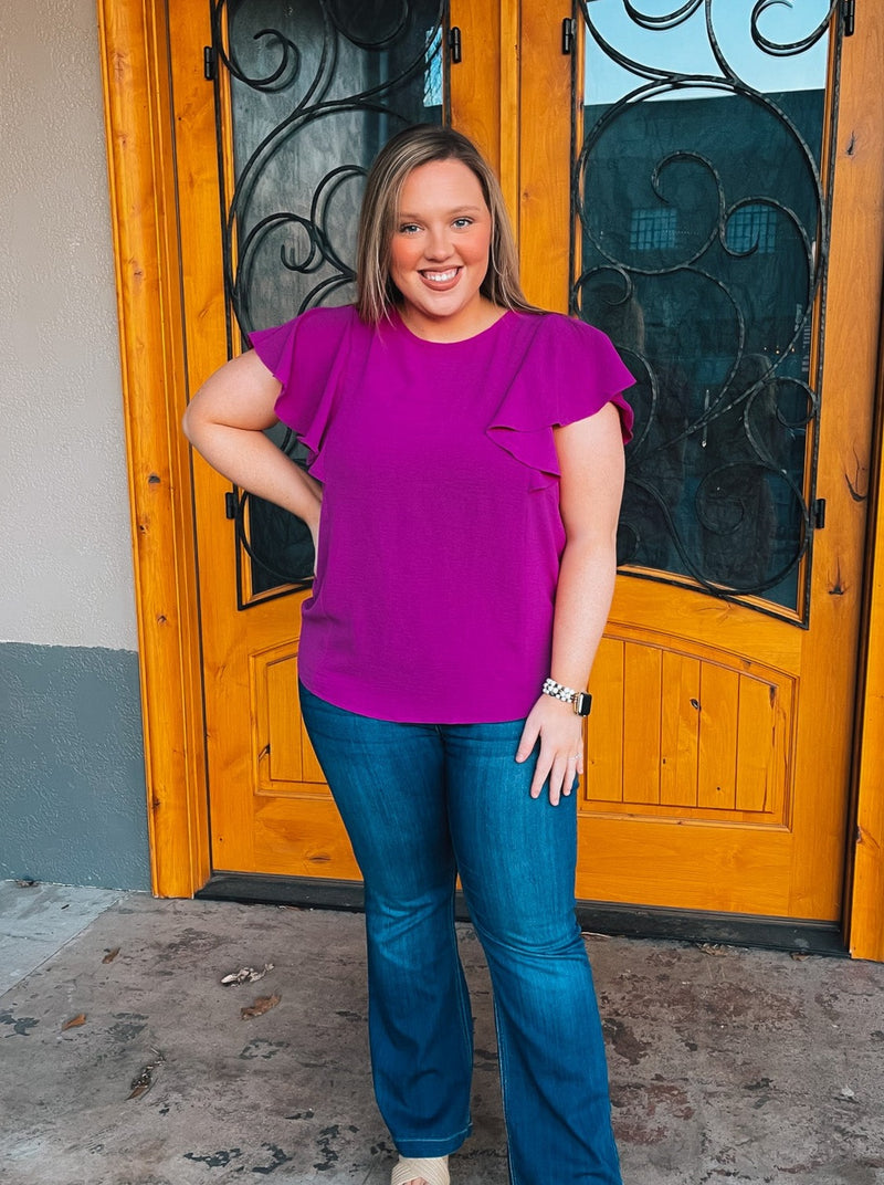 Top features a beautiful purple color, short ruffle sleeves, round neck line, stretchable fabric, and runs true to size!