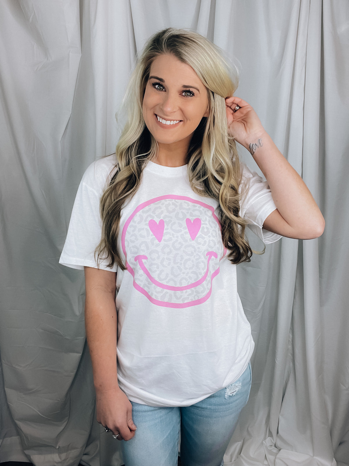 Graphic tee features a solid base colored tee, grey leopard print happy face with pink detailing, short sleeves, unisex fit, round neck line, legging length approval and runs true to size! 