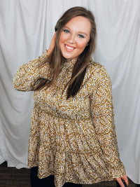 Top features a mustard base, long sleeves, white and black spotted detail, ruffle detail, round neck line, button closure and runs true to size! 