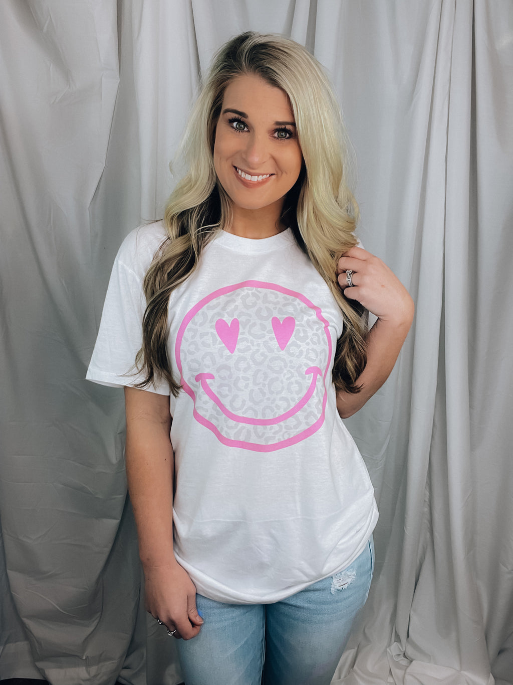 Graphic tee features a solid base colored tee, grey leopard print happy face with pink detailing, short sleeves, unisex fit, round neck line, legging length approval and runs true to size! 