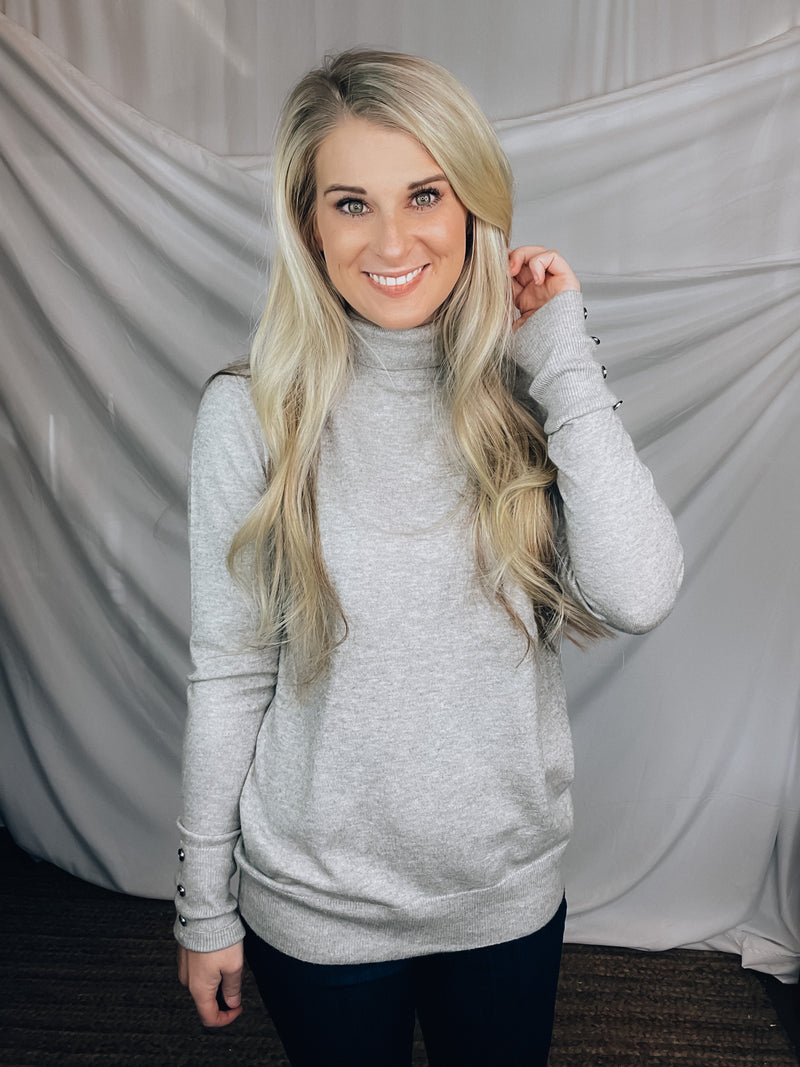 Sweater features a heather grey color, long sleeves, basic turtle neck ,long sleeves, cuff buttons and runs true to size! 